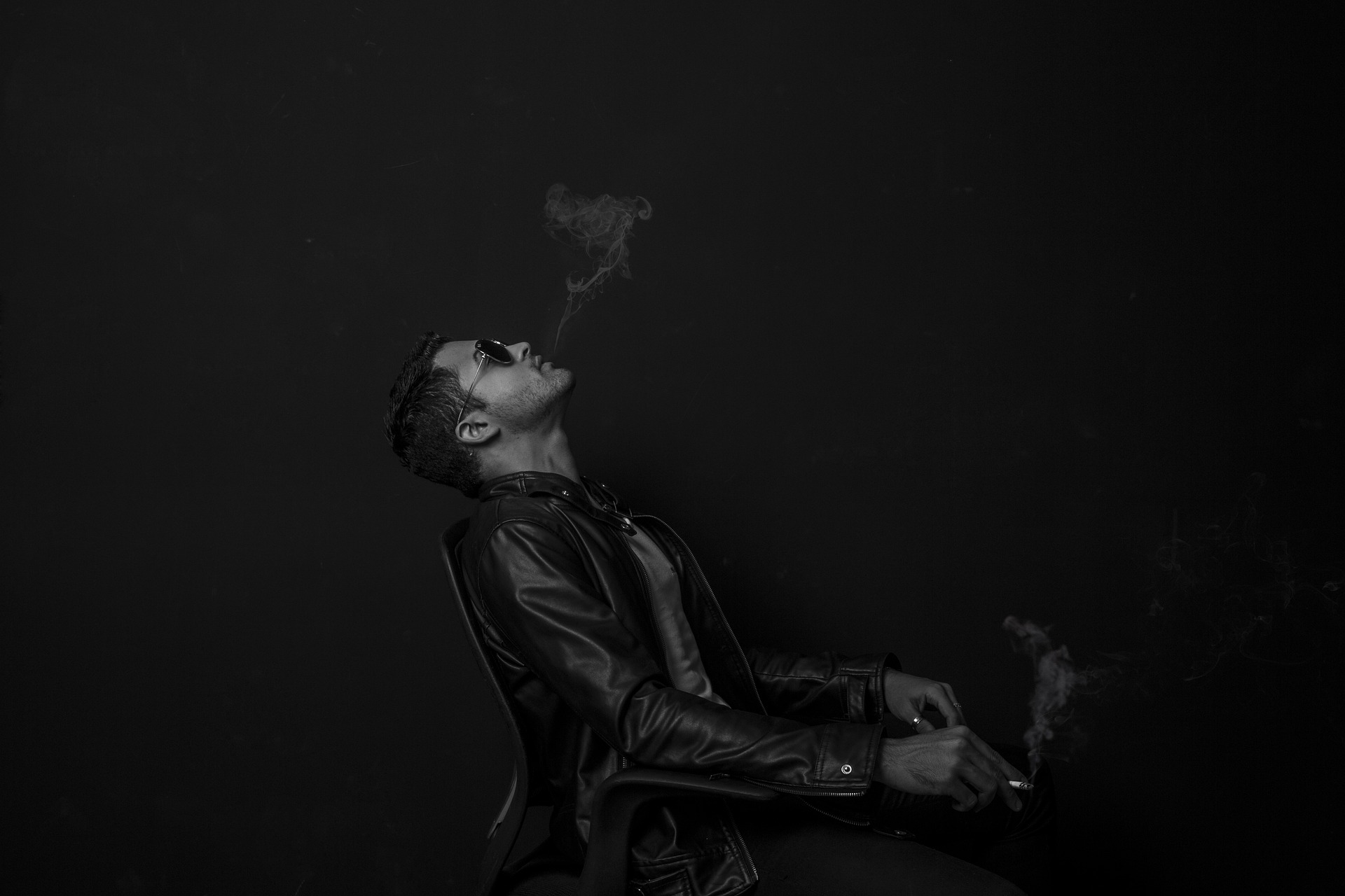 man in chair smoking with sunglasses and leather jacket