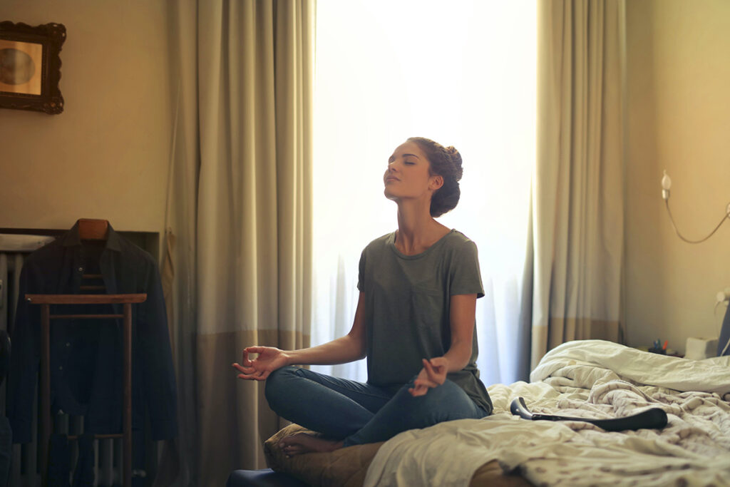 young woman meditation on her bed as a part of a morning routine